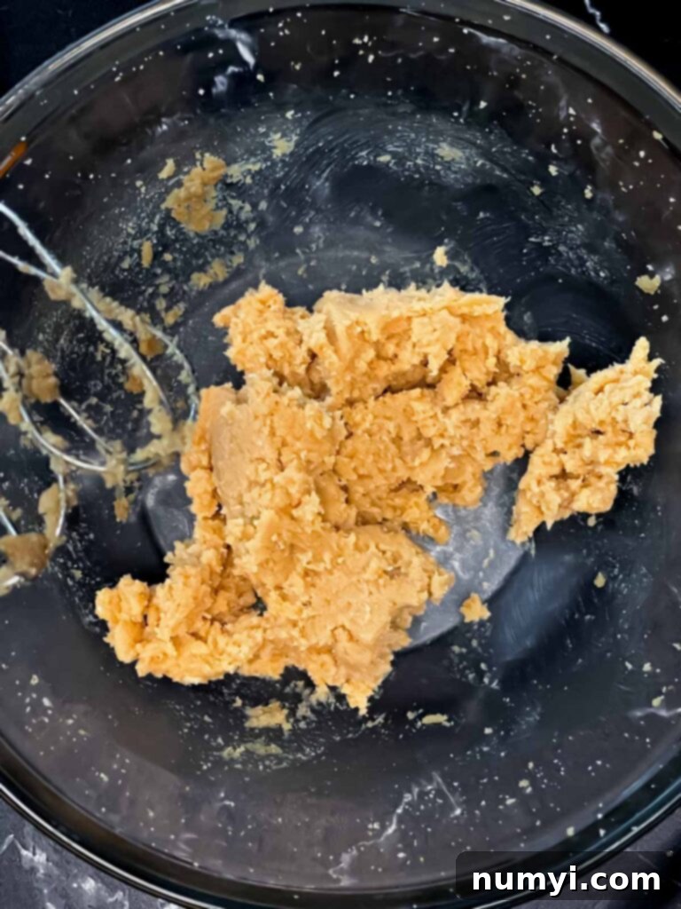 Butter and sugars creamed together in a glass mixing bowl for apple cider muffins.