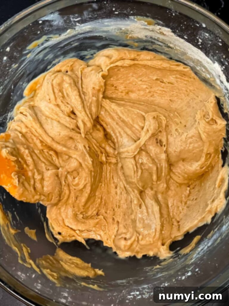 Apple cider muffins batter mixed in a glass mixing bowl.