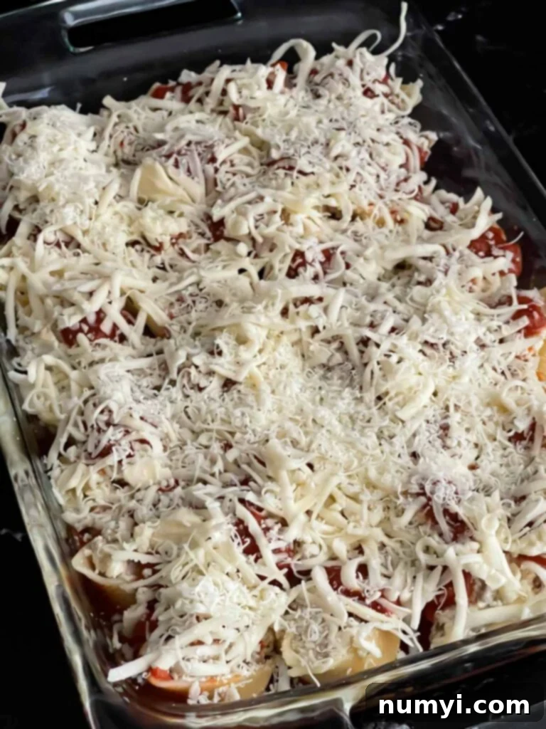 A casserole dish filled with unbaked Italian sausage stuffed shells, covered with marinara and mozzarella cheese, ready to be placed in the oven.