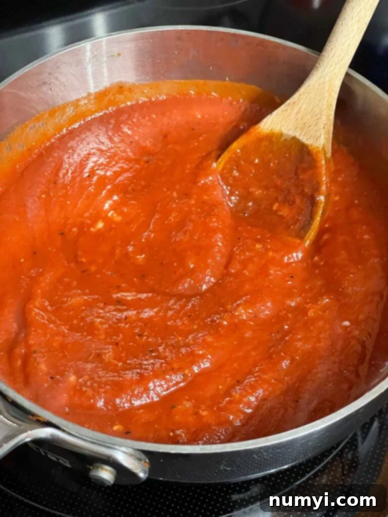 A saucepan filled with rich, bubbling homemade marinara sauce, ready for use.