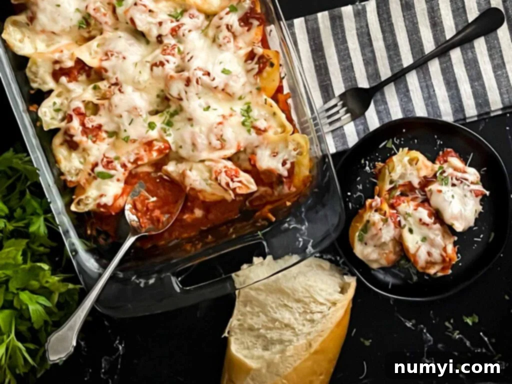 Close-up of baked Italian sausage stuffed shells in a white ceramic baking dish, showcasing the melted cheese and rich marinara sauce, ready to be served.