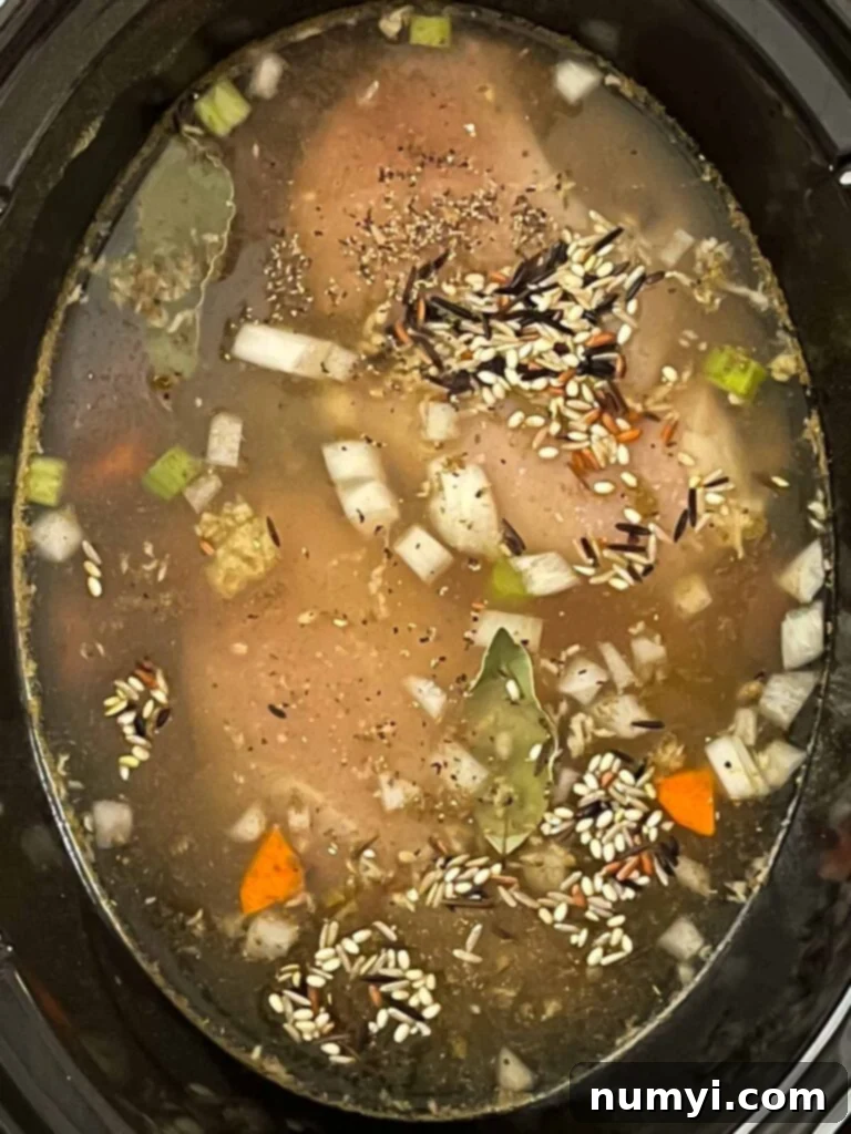 Slow cooker chicken and wild rice soup ingredients in the crock of a slow cooker.