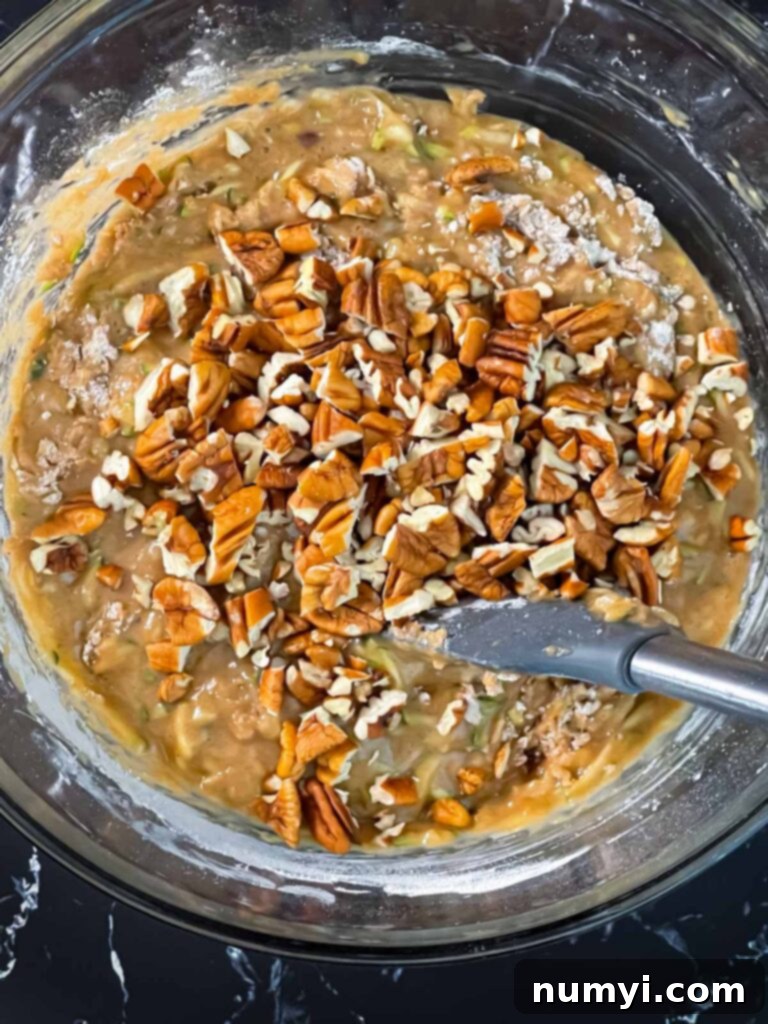 Moist Zucchini Bread 7 Chopped pecans added to the zucchini bread batter in a glass bowl.