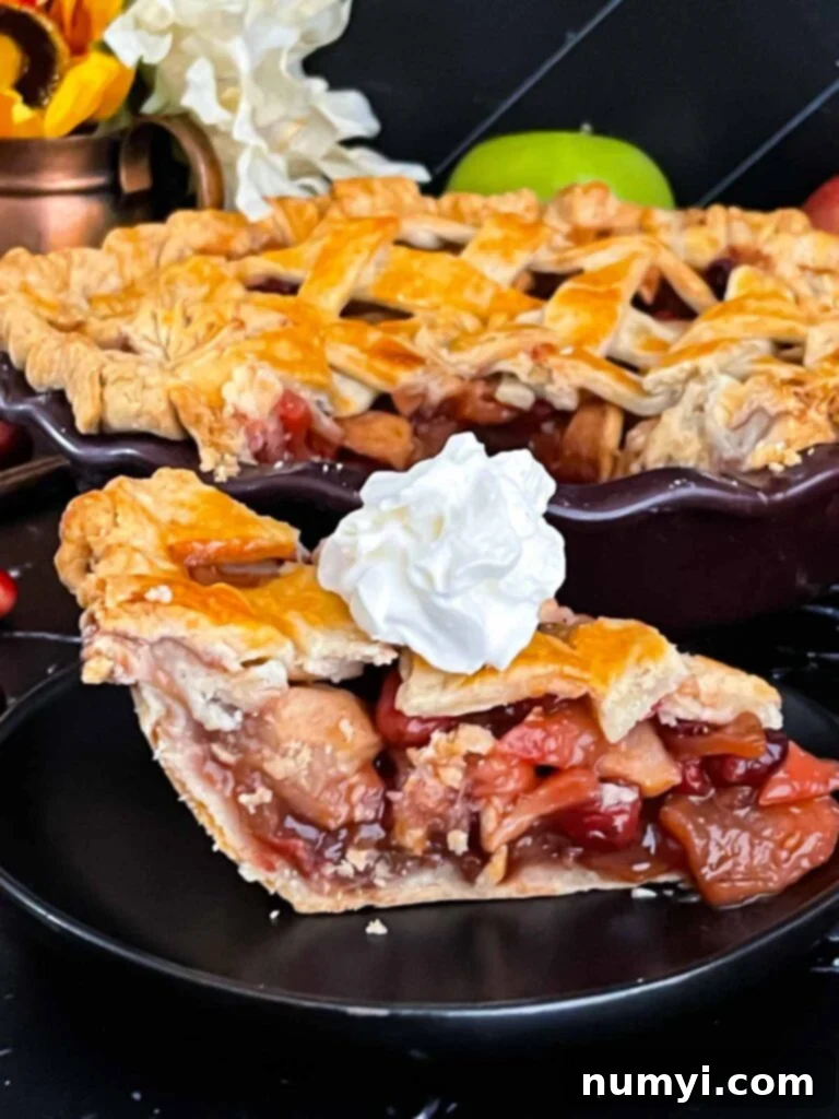A delectable slice of cranberry apple pie, beautifully plated with a generous dollop of whipped cream, ready to be enjoyed.