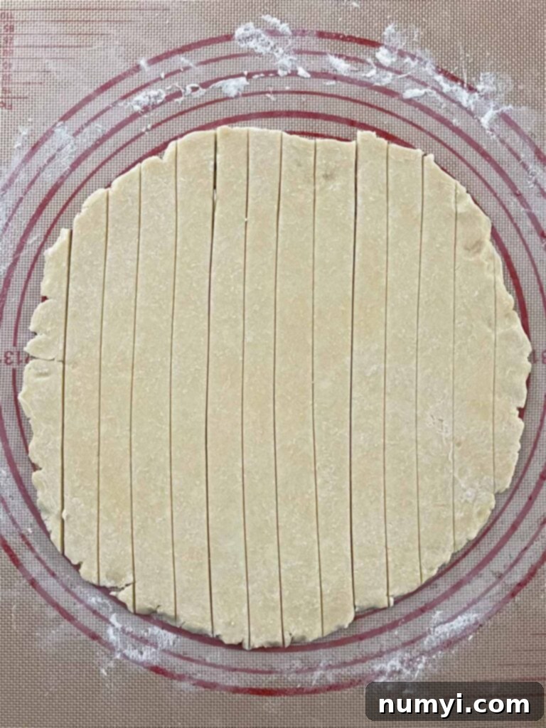 Pie dough strips precisely cut, laid out on a dark surface, ready to be woven into a beautiful lattice crust.