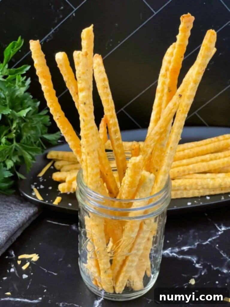 Crispy Cheddar Herb Sticks 15 An inviting display of crisp cheddar and herb cheese straws arranged in a clear mason jar, perfect for serving or gifting.