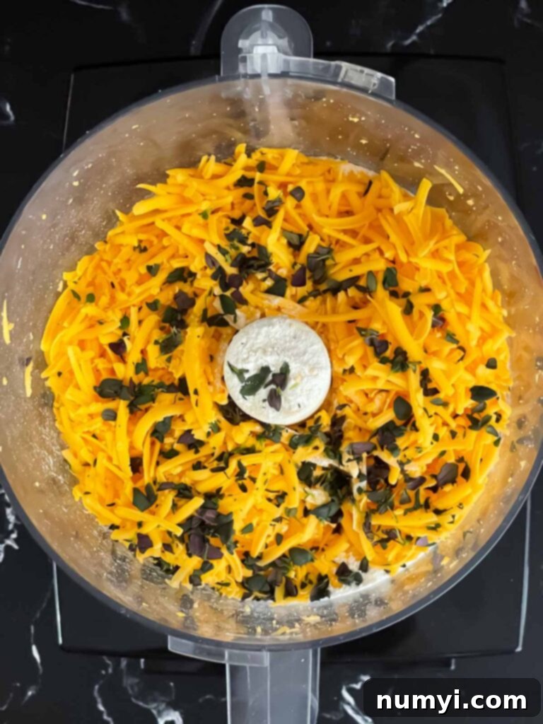 Crispy Cheddar Herb Sticks 5 A mix of finely grated cheddar cheese, vibrant fresh herbs, and dry ingredients like flour in a food processor, ready for pulsing.