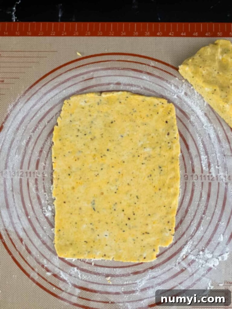 Crispy Cheddar Herb Sticks 10 A portion of cheddar and herb dough rolled out thinly into a perfect rectangle on a dough mat, demonstrating ideal consistency for cutting cheese straws.