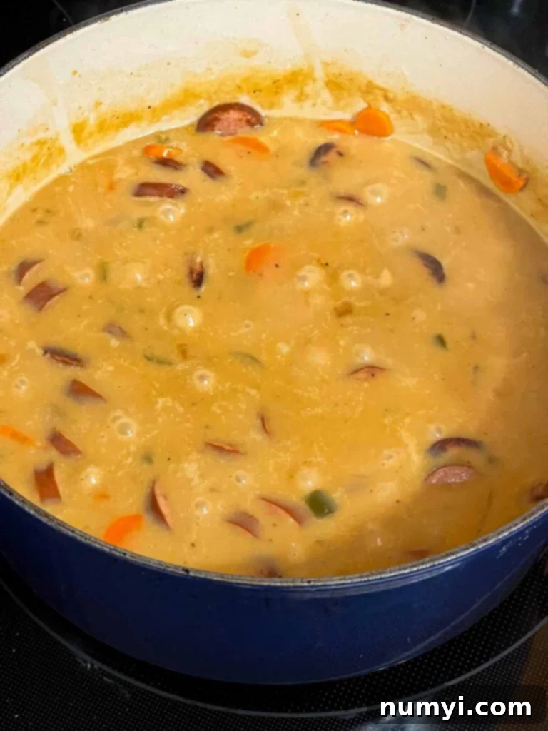 The finished creamy bean soup with smoked sausage simmering gently, ready to be served.