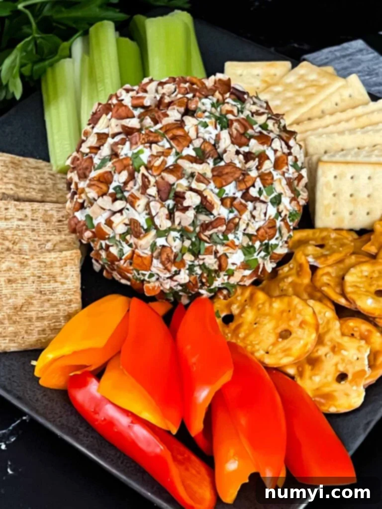 Creamy Garlic Herb Cheese Ball 8 A garlic herb cheese ball on a black plate with crackers and vegetables.