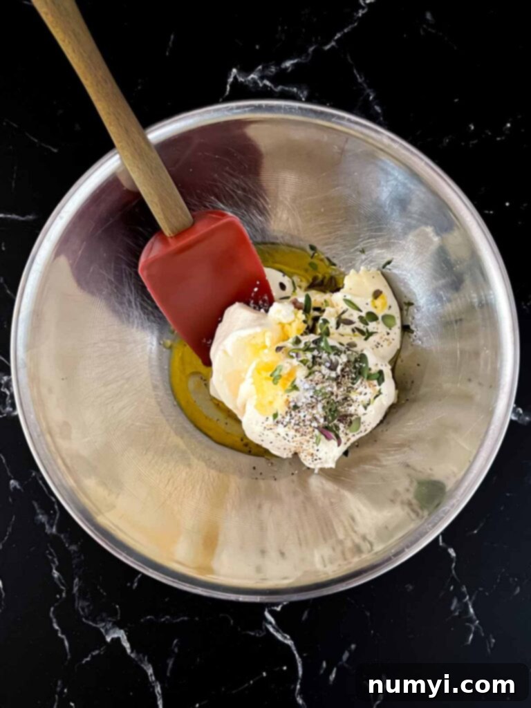 Creamy Baked Ricotta 6 A bowl filled with the creamy ricotta dip mixture, featuring minced garlic, lemon, and fresh thyme, before baking.