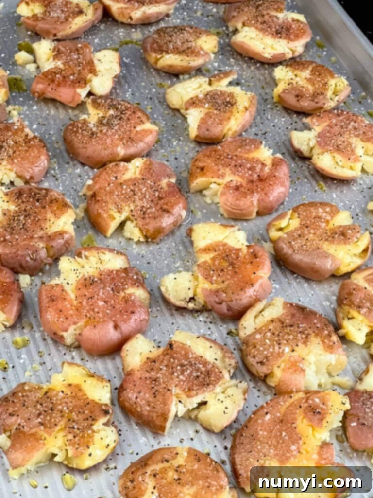Season smashed potatoes on a baking sheet pan.