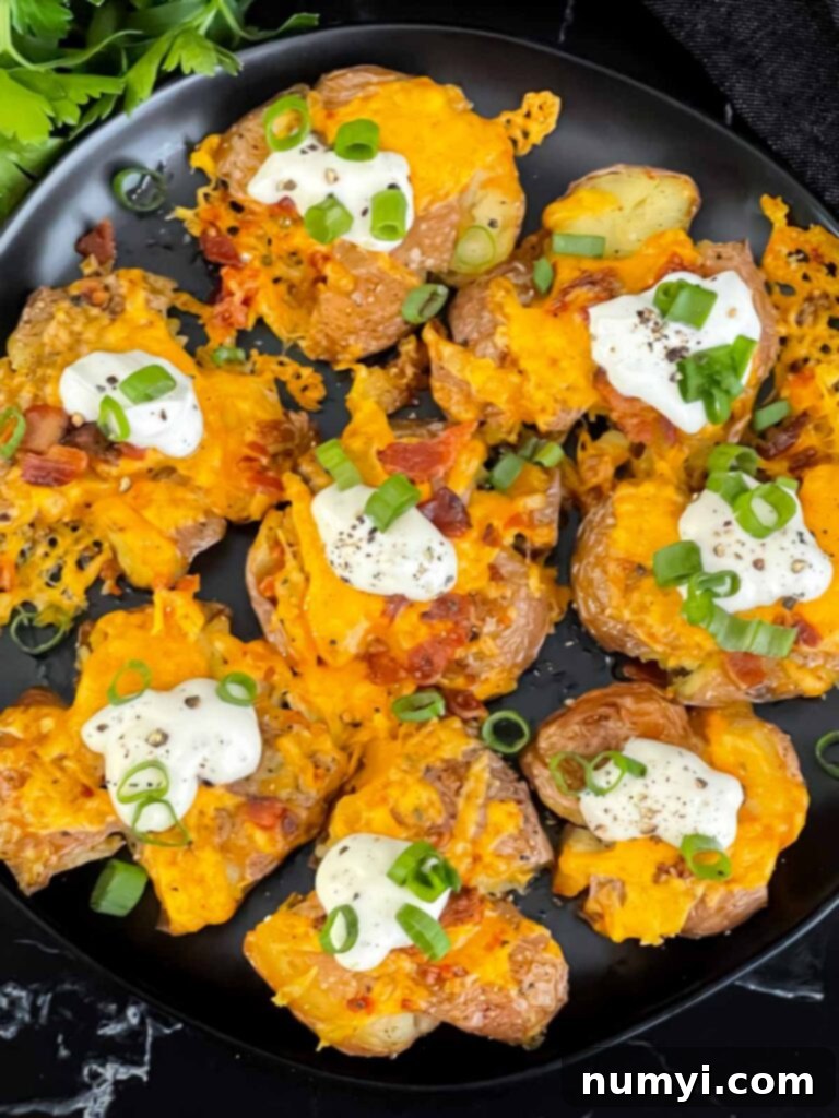 Loaded smashed potatoes on a black serving plate.