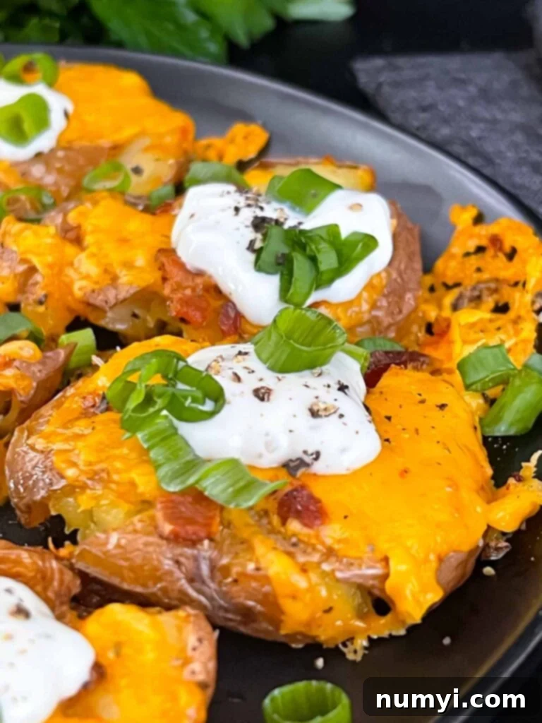 Loaded smashed potatoes on a black serving plate.