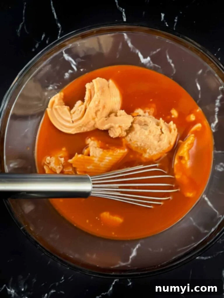Refried beans and enchilada sauce separately in a clear glass bowl.