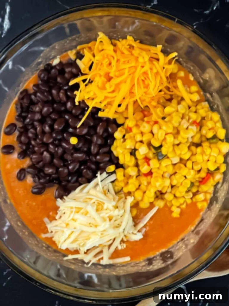 Various chicken enchilada casserole ingredients mixed in a bowl before adding rice.