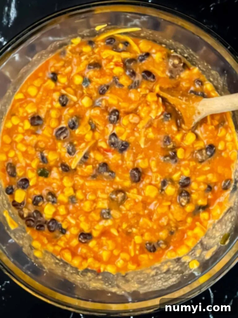 All chicken enchilada rice casserole ingredients, except rice, combined in a bowl.