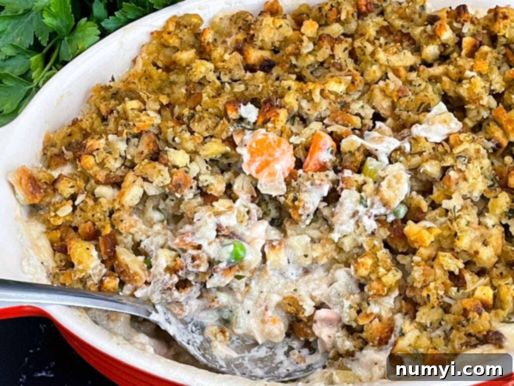 A golden brown Chicken Stuffing Casserole in a white baking dish, ready to be served.
