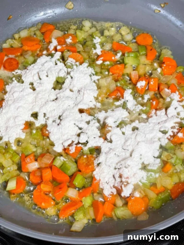 Adding all-purpose flour to the sautéed mirepoix and melted butter in a skillet.