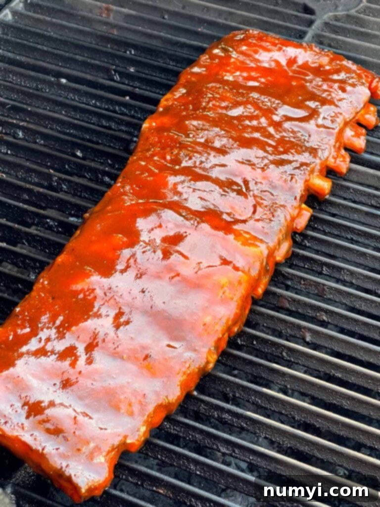 Sauced ribs on the smoker grates, caramelizing under the heat.