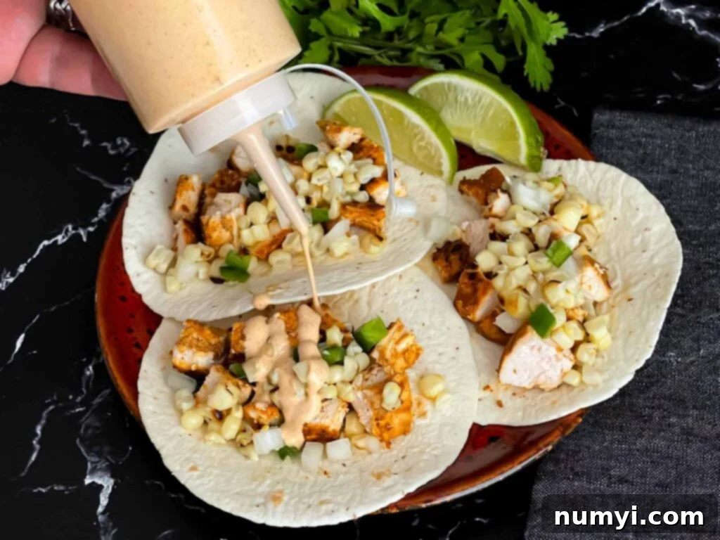 Adding a southwest sauce to grilled chicken tacos.