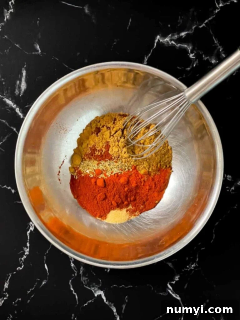 Unmixed Southwest spices, including various chili powders, cumin, and paprika, in a stainless steel bowl.
