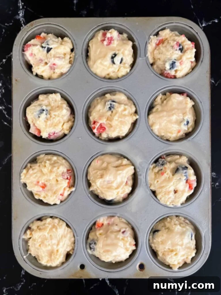 Mixed berry muffins in a muffin tin ready to be baked.