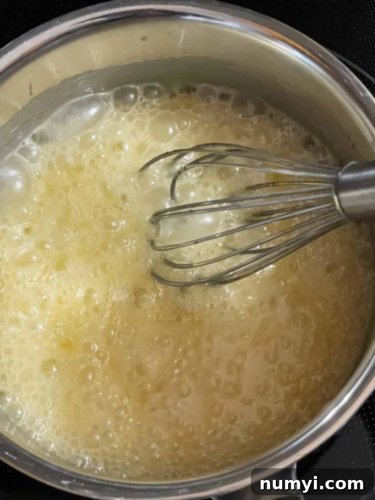 An Amaretto glaze cooking in a saucepan, showing its smooth, shimmering texture.
