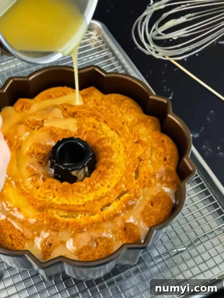 Pouring a warm Amaretto glaze over a freshly baked pound cake in a bundt pan.