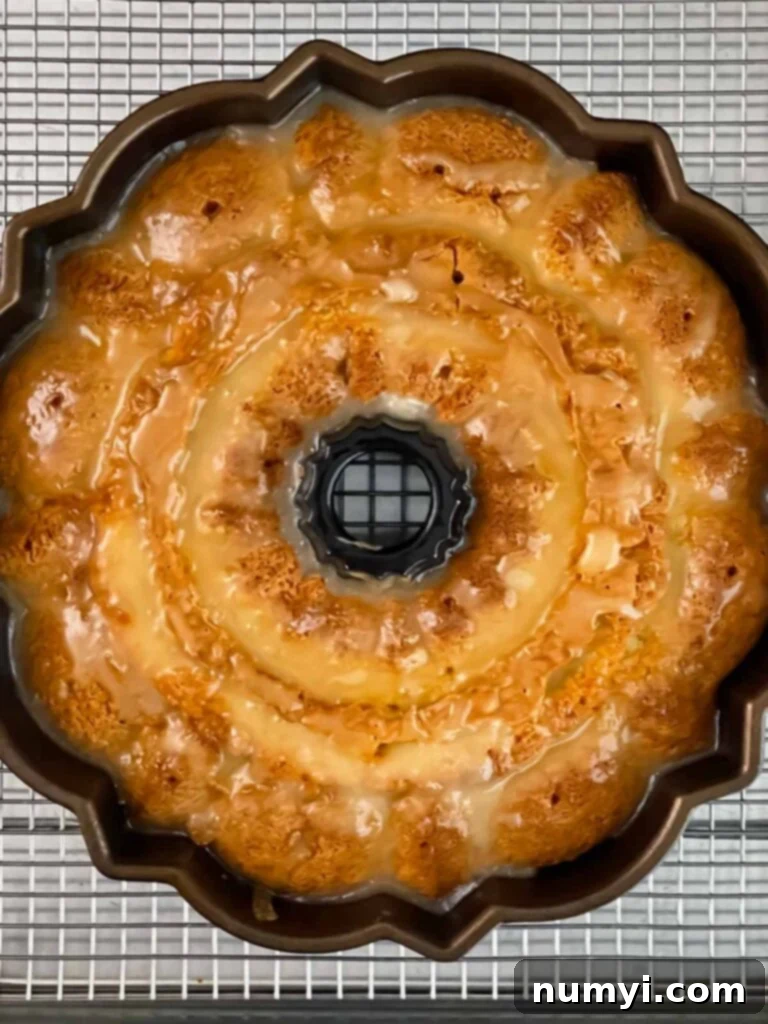 Amaretto pound cake with a glaze added, cooling on a wire rack.