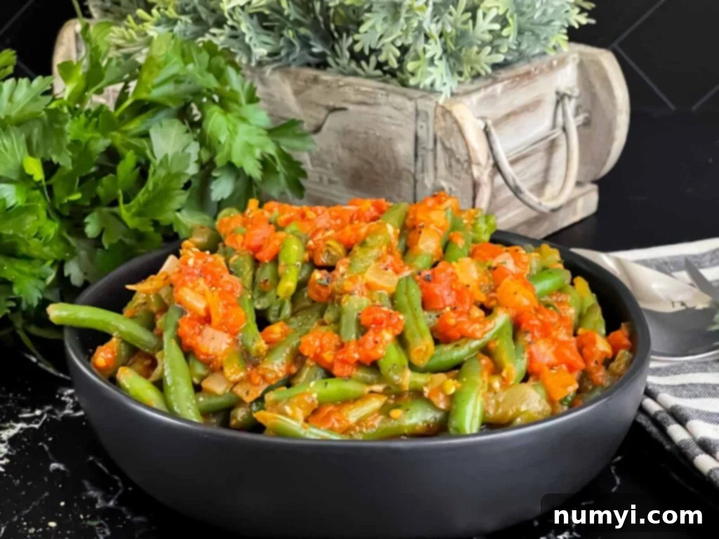 Green beans with tomato sauce in a dark bowl.