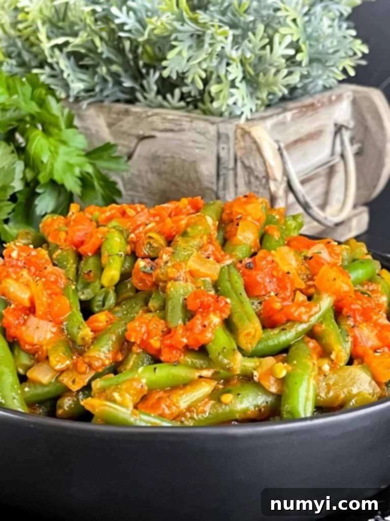 Green beans with tomato sauce in a dark bowl.