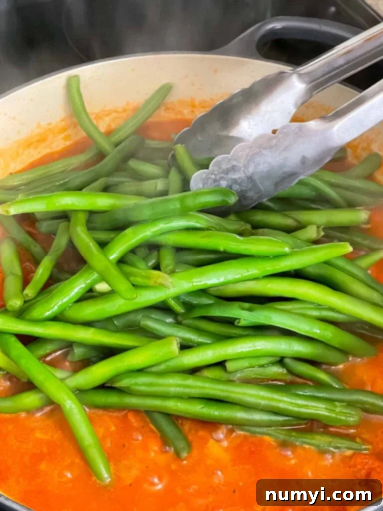 Adding green beans to tomato sauce.