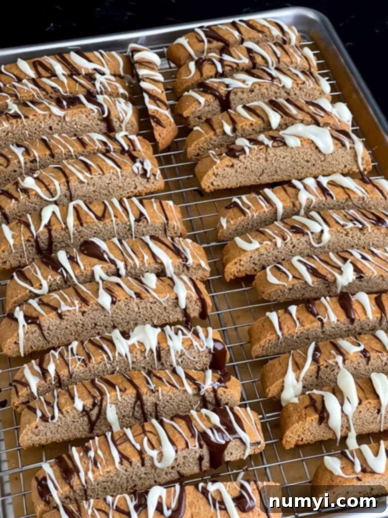Chai biscotti with a chocolate drizzle on a wire rack.