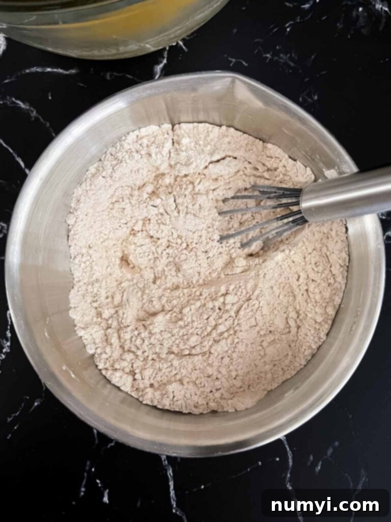 Dry ingredients being mixed in a stainless steel bowl.