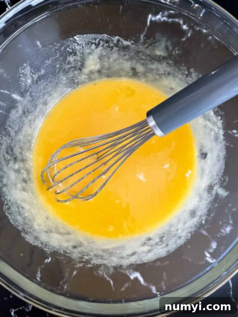 Egg, butter, and sugar mixture in a glass bowl.