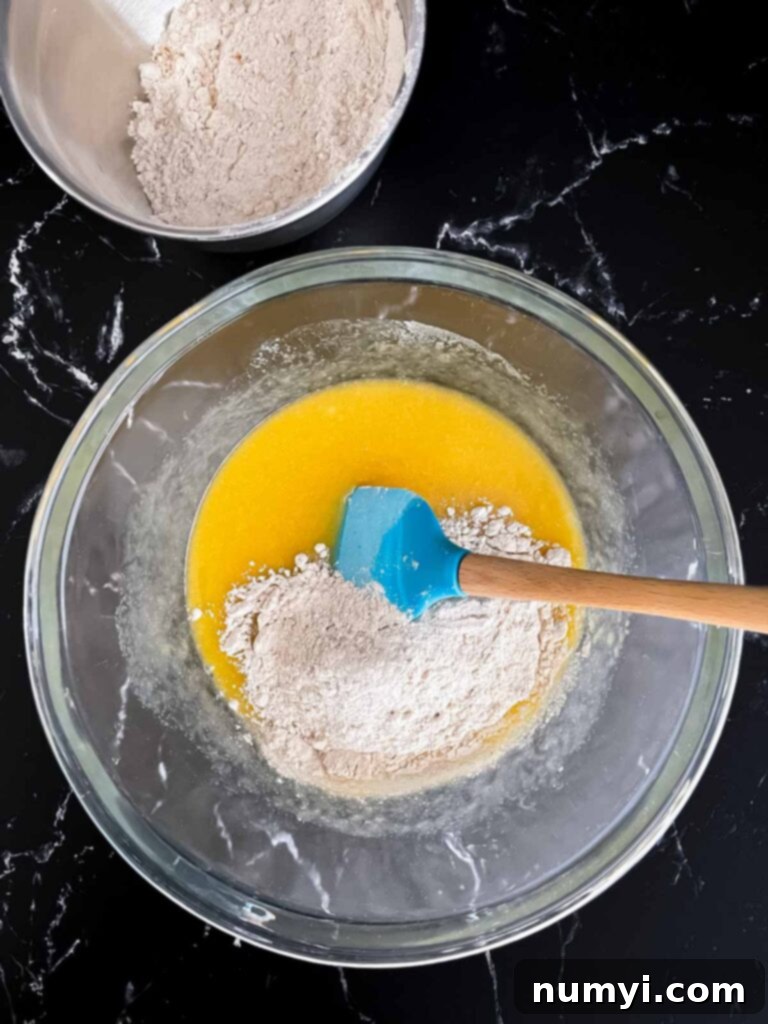 Flour added to a butter egg mixture in a glass bowl.