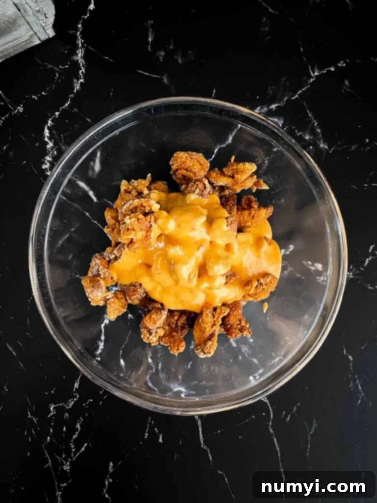 Bang Bang chicken being mixed together in glass bowl.