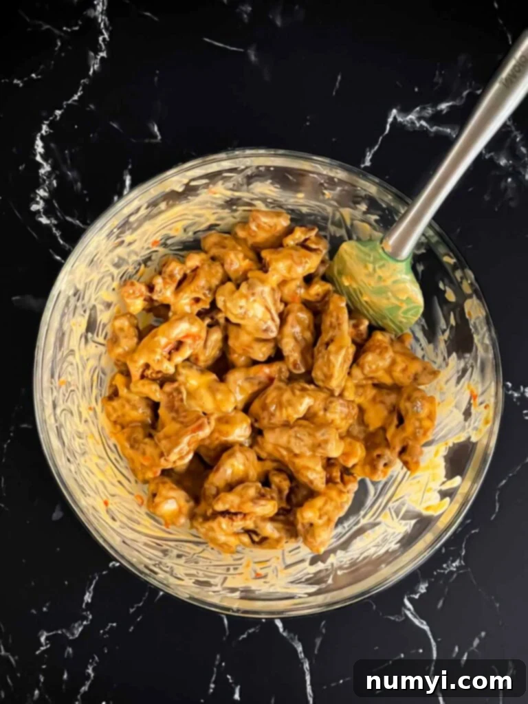 Bang Bang chicken being mixed together in glass bowl.