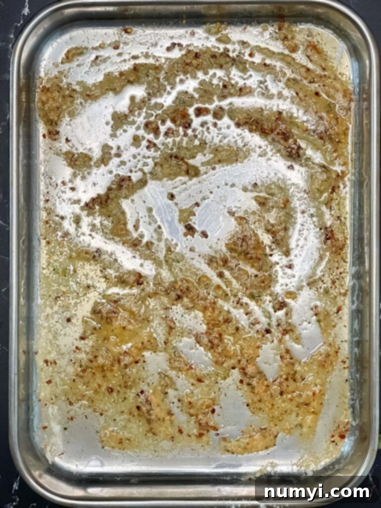 Melted butter and spices in a large baking dish, ready for mixing.