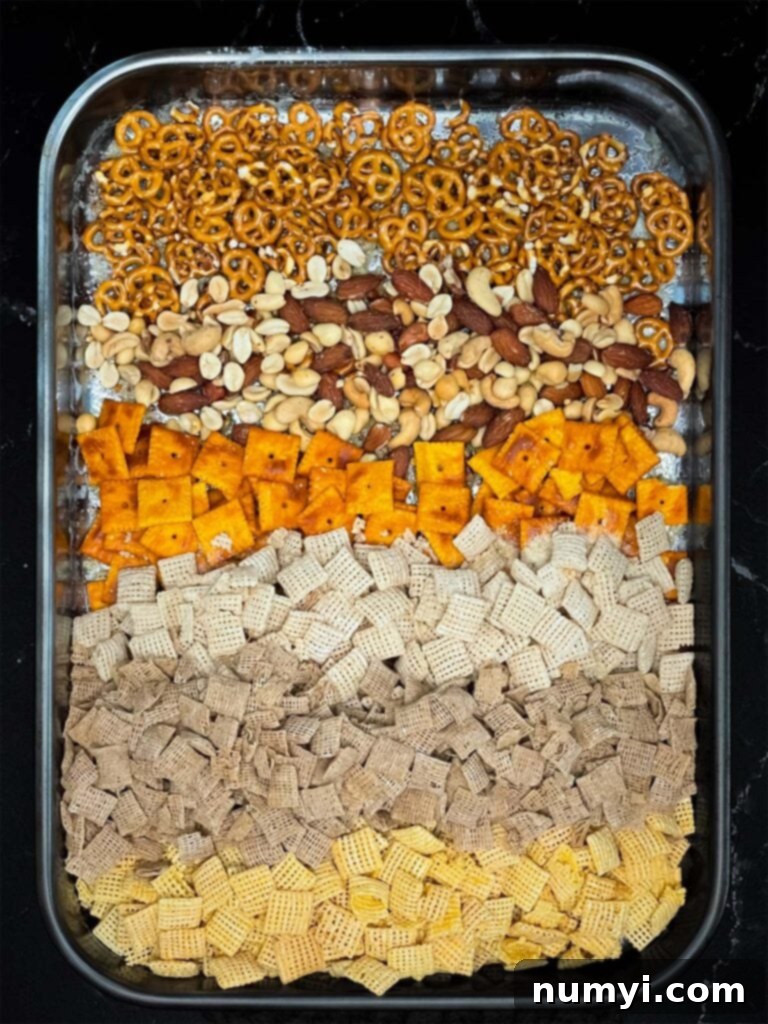 All ingredients for Firecracker Chex Mix combined in a baking dish, ready for the oven.