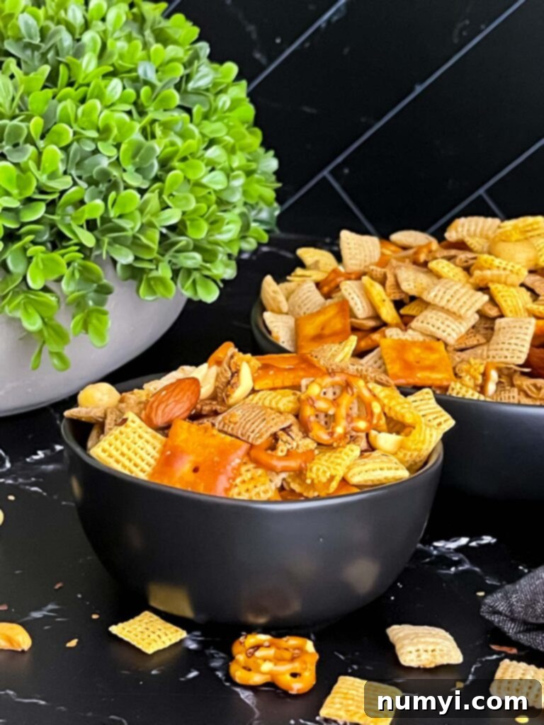 Close-up of Firecracker Chex Mix in a dark bowl, showing the spicy seasoning.