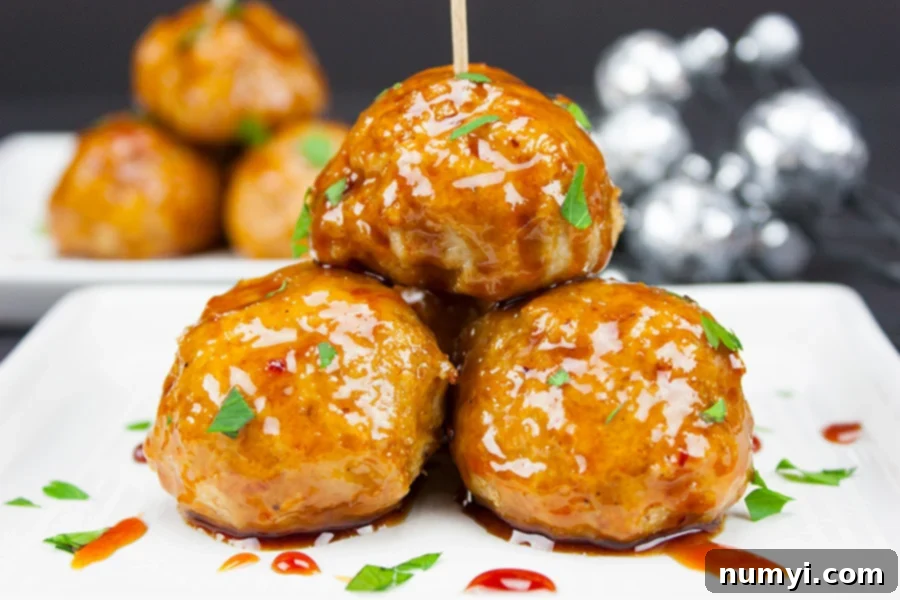 Firecracker chicken meatballs, glossy with a spicy-sweet sauce, served with sesame seeds and green onions.