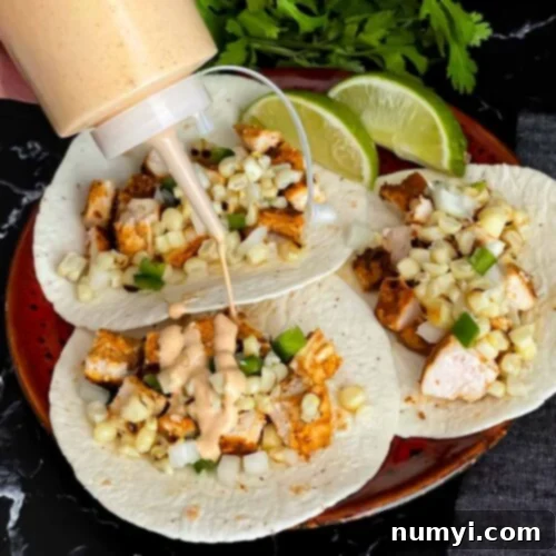 Adding a southwest sauce to grilled chicken tacos.