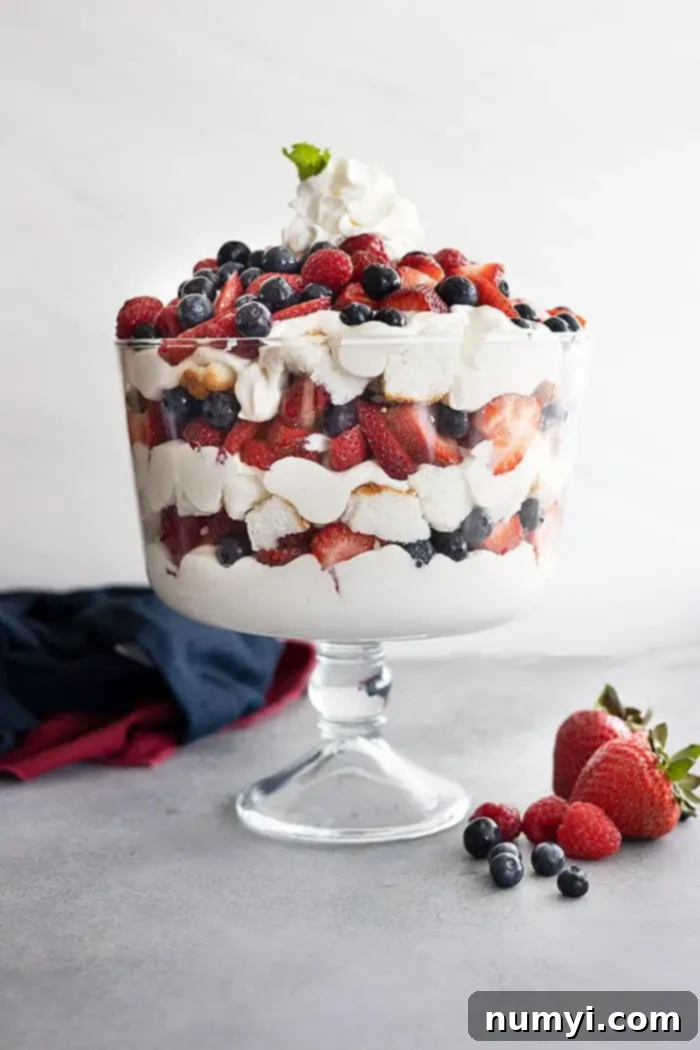 A trifle bowl filled with angel food cake, coconut cheesecake filling, strawberries, blueberries, and raspberries. All in pretty layers.