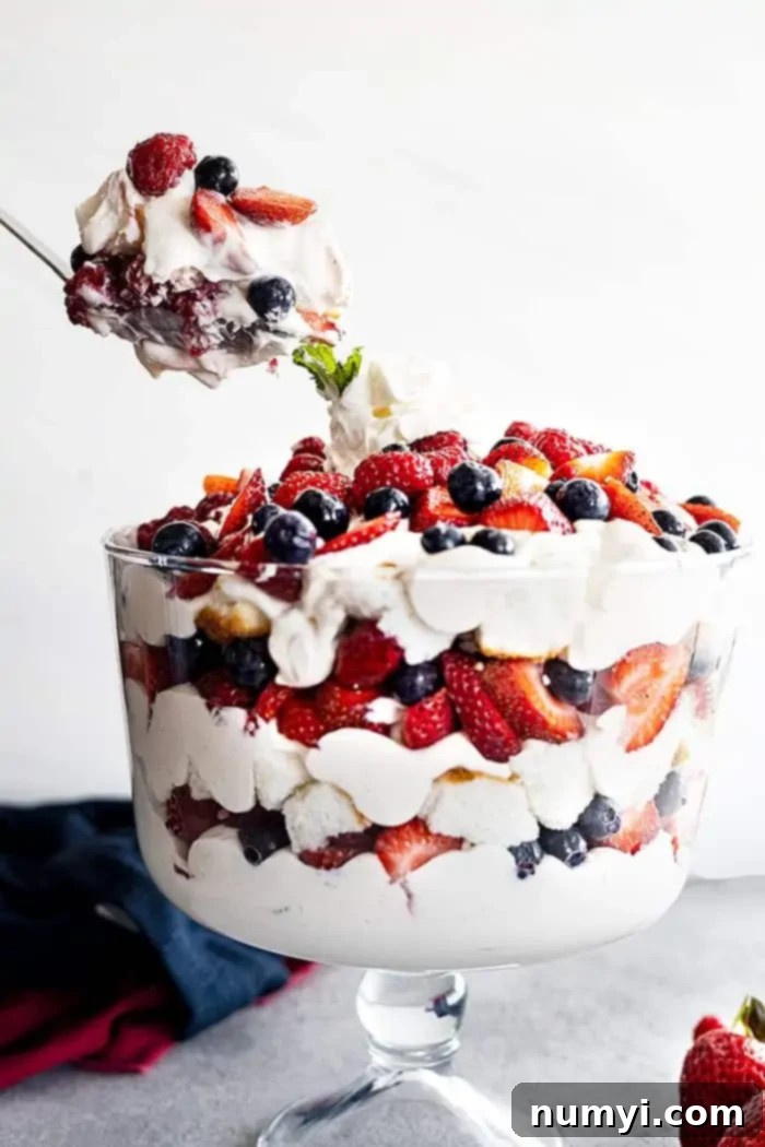 A large spoon dishing up a portion of berry coconut trifle.