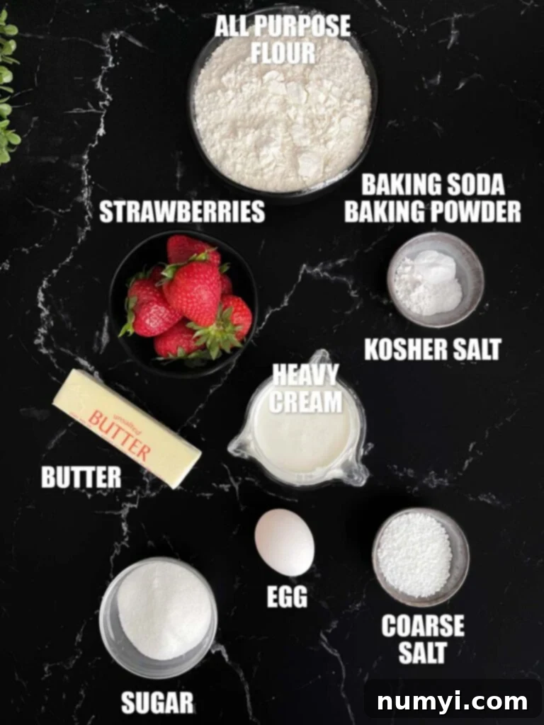 Luscious Strawberry Scones 3 Various ingredients for baking strawberry scones, including flour, sugar, butter, and fresh strawberries, laid out on a white surface.