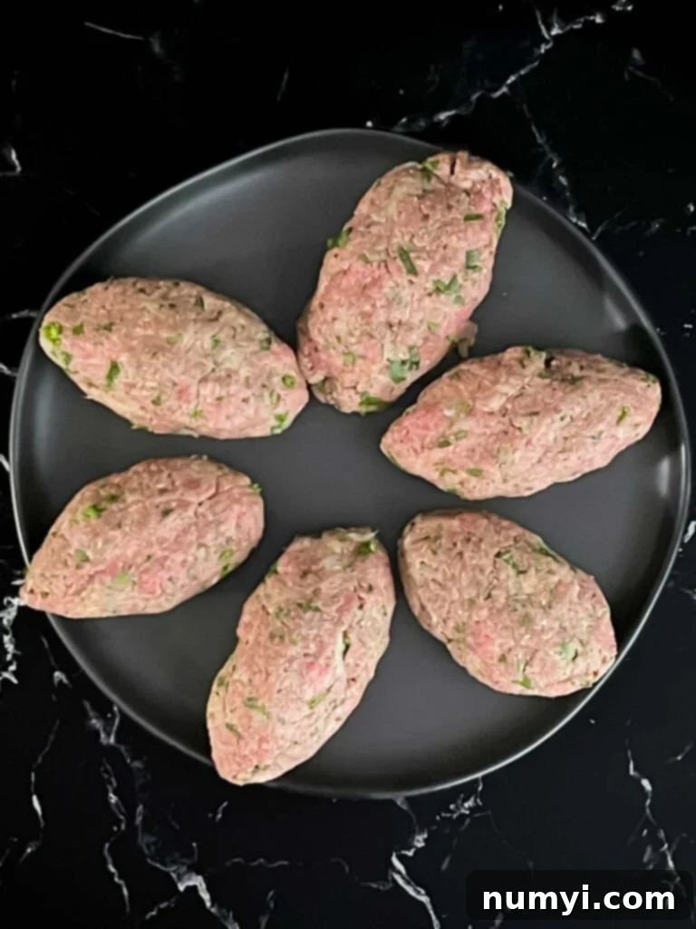 Kofte shaped into ovals on a black plate.