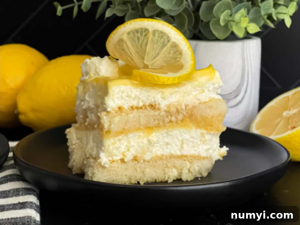 A serving of Limoncello tiramisu on a dark plate, placed on a dark surface, showcasing its beautiful layers.