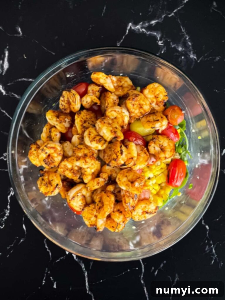 Fresh Grilled Shrimp and Corn Salad 14 Close-up of grilled shrimp on top of a vibrant salad in a glass bowl.
